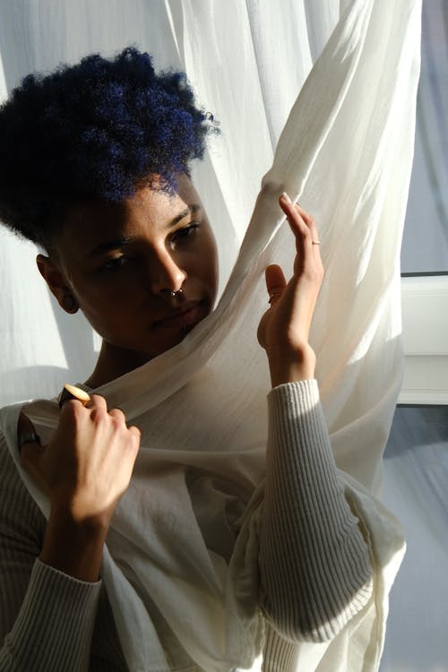 A woman with blue hair is holding a white sheet