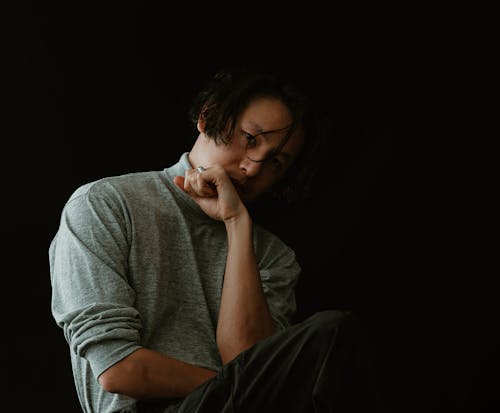 A man sitting on the ground with his hand on his chin