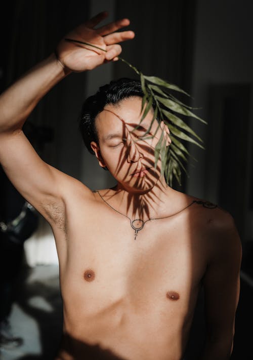 A shirtless man with a leaf on his head