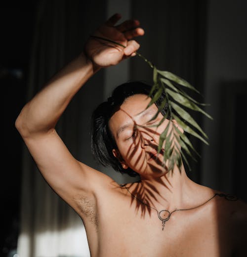 A shirtless man with a leaf on his head