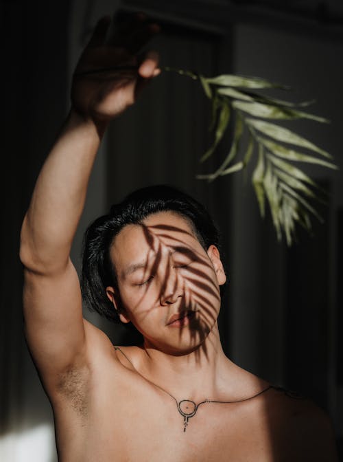 A shirtless man with a leaf on his head