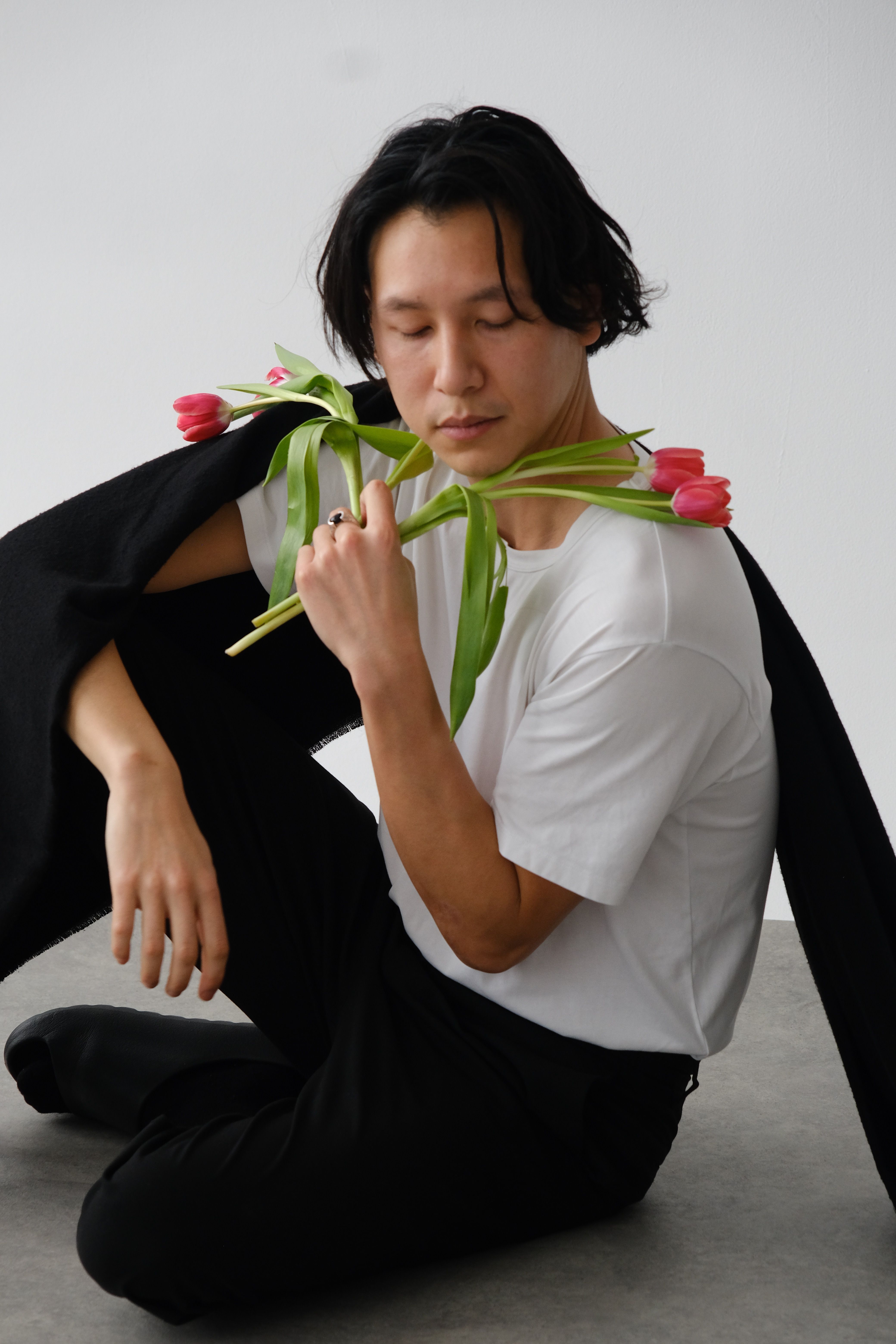 Artistic studio portrait of a man in a minimalist style posing with tulips.
