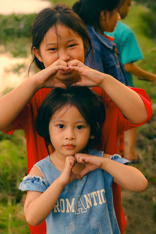 Free Two children smiling and making heart gestures outdoors, showcasing joy and friendship. Stock Photo