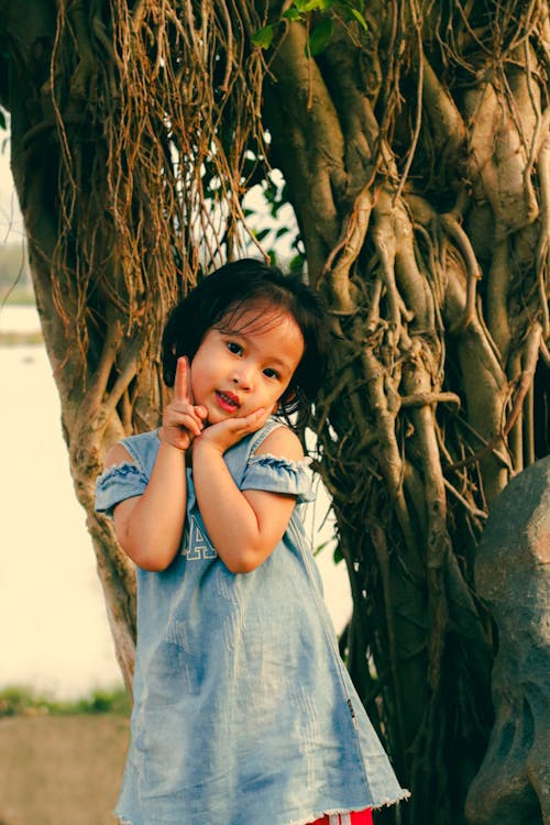 Free A little girl posing for a picture in front of a tree Stock Photo