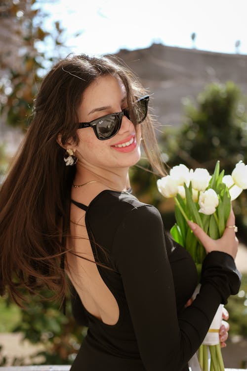 A woman in sunglasses holding tulips