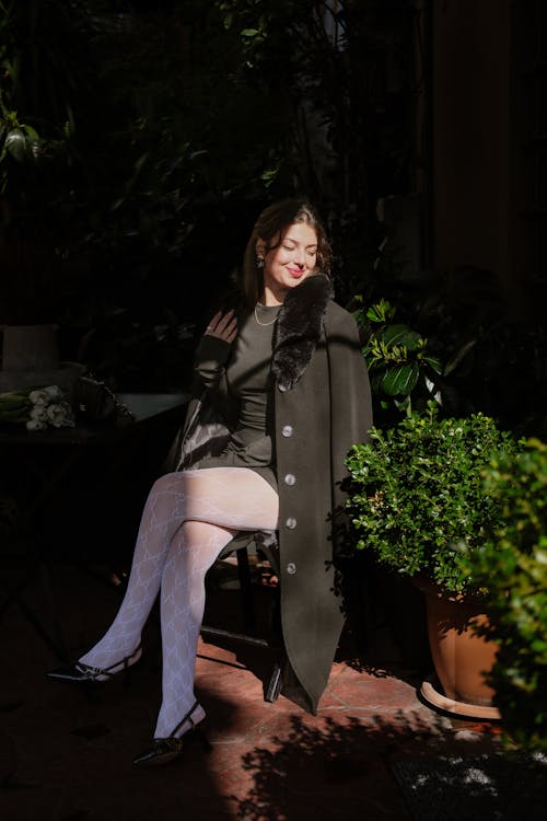 Smiling Woman Sitting in Black Coat and Tights