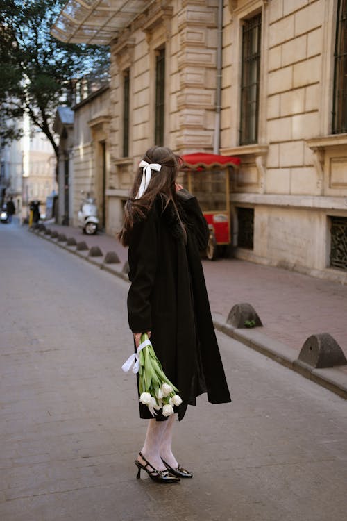 Elegant Woman Standing on a Street with a Bunch of White Tulips 