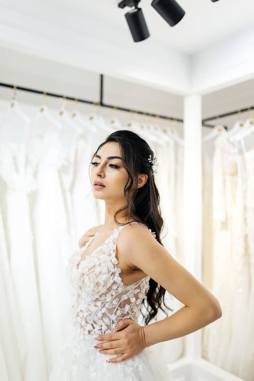 A woman in a wedding dress standing in front of a rack of wedding dresses