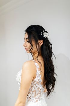 A beautiful bride in an elegant lace wedding dress posing with floral hair accessories.
