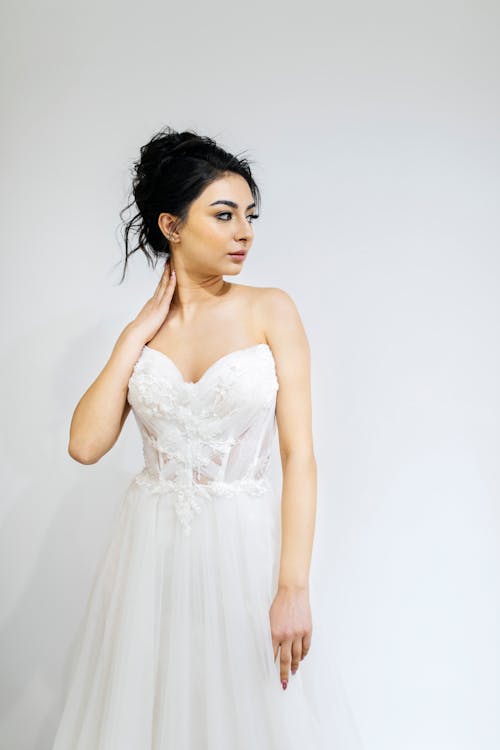 A woman in a wedding dress poses for a photo