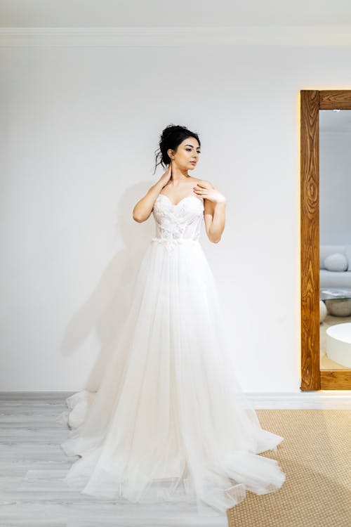 A woman in a wedding dress standing in front of a mirror