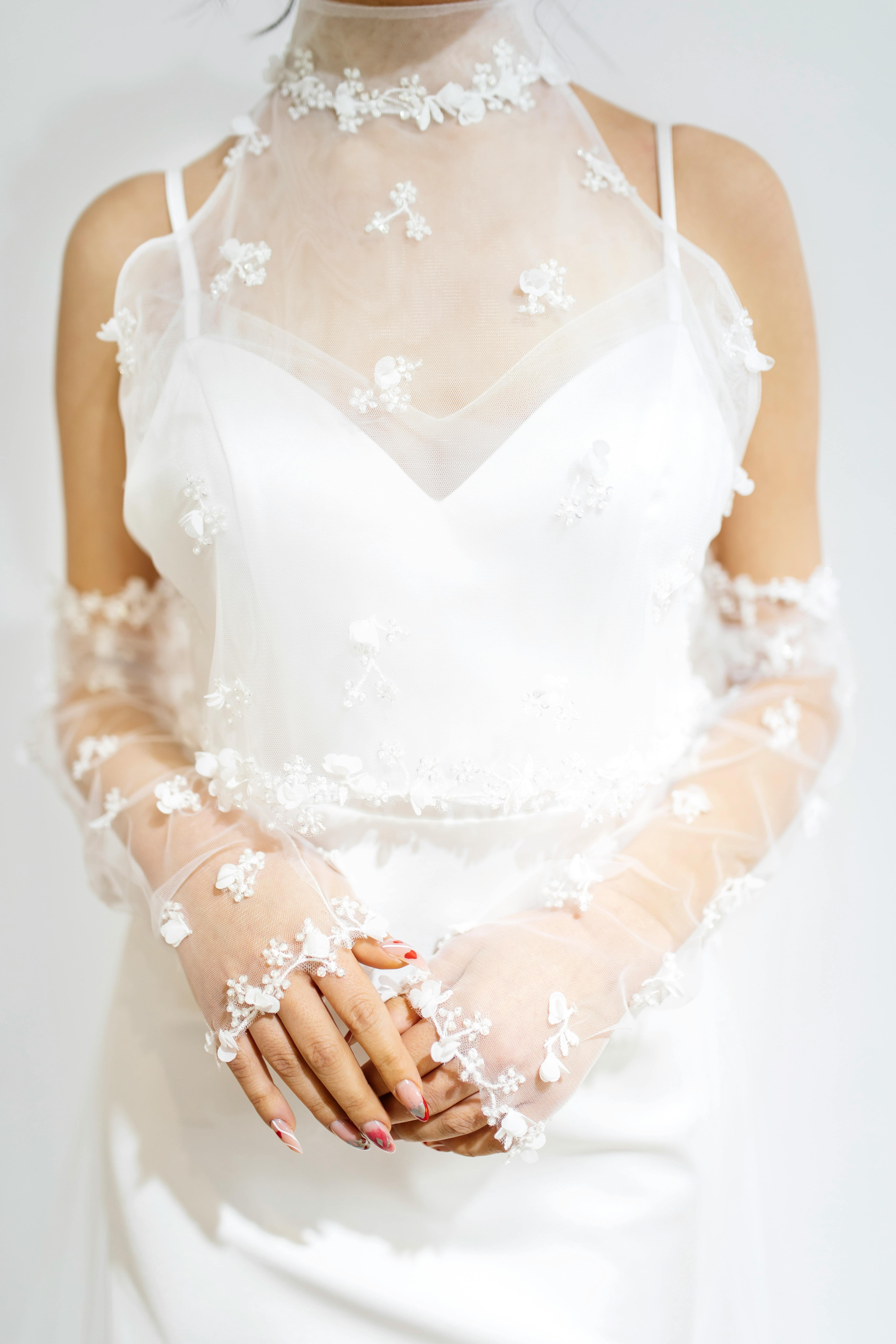 Close-up of a bride's white dress featuring intricate floral embroidery.