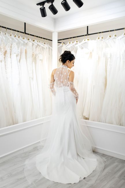 A bride posing in an elegant wedding dress inside a chic bridal shop, showcasing modern bridal fashion.