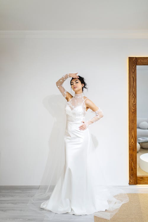 A woman in a wedding dress poses for a photo
