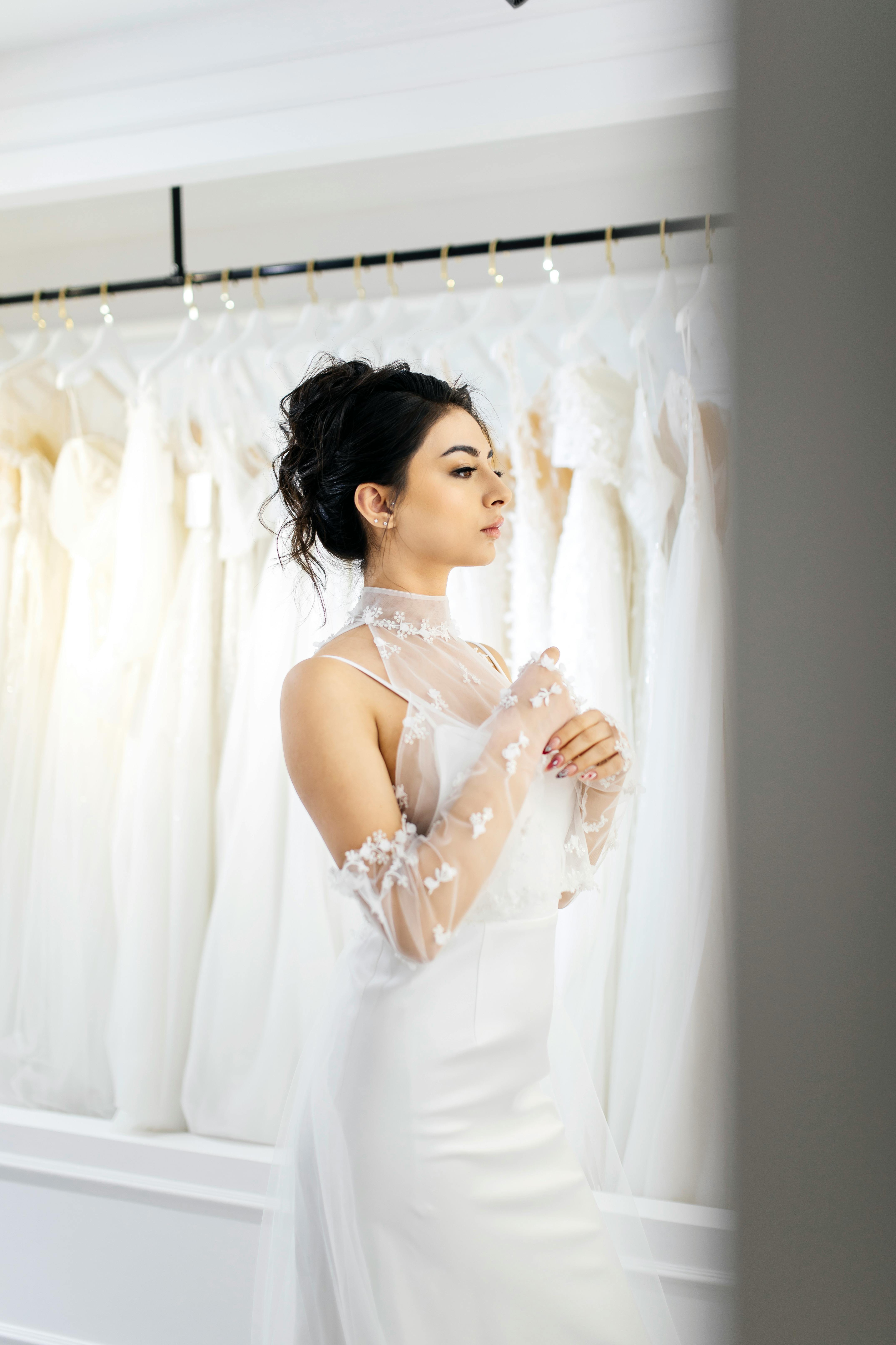 Bride in elegant white dress during wedding preparations in a bridal shop.