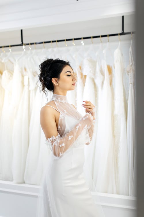 A woman in a wedding dress standing in front of racks of wedding dresses