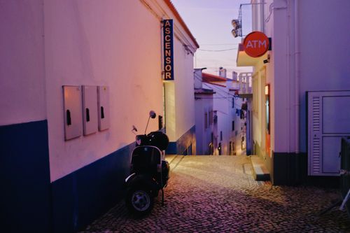 Free A picturesque scooter parked on a cobblestone street in Nazaré at twilight. Stock Photo