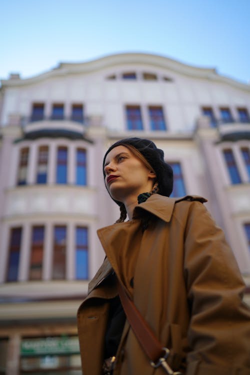 A woman in a trench coat standing in front of a building