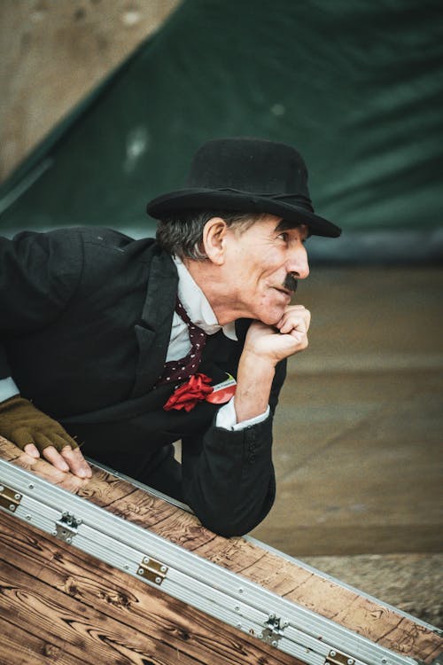 A man in a top hat leaning on a suitcase