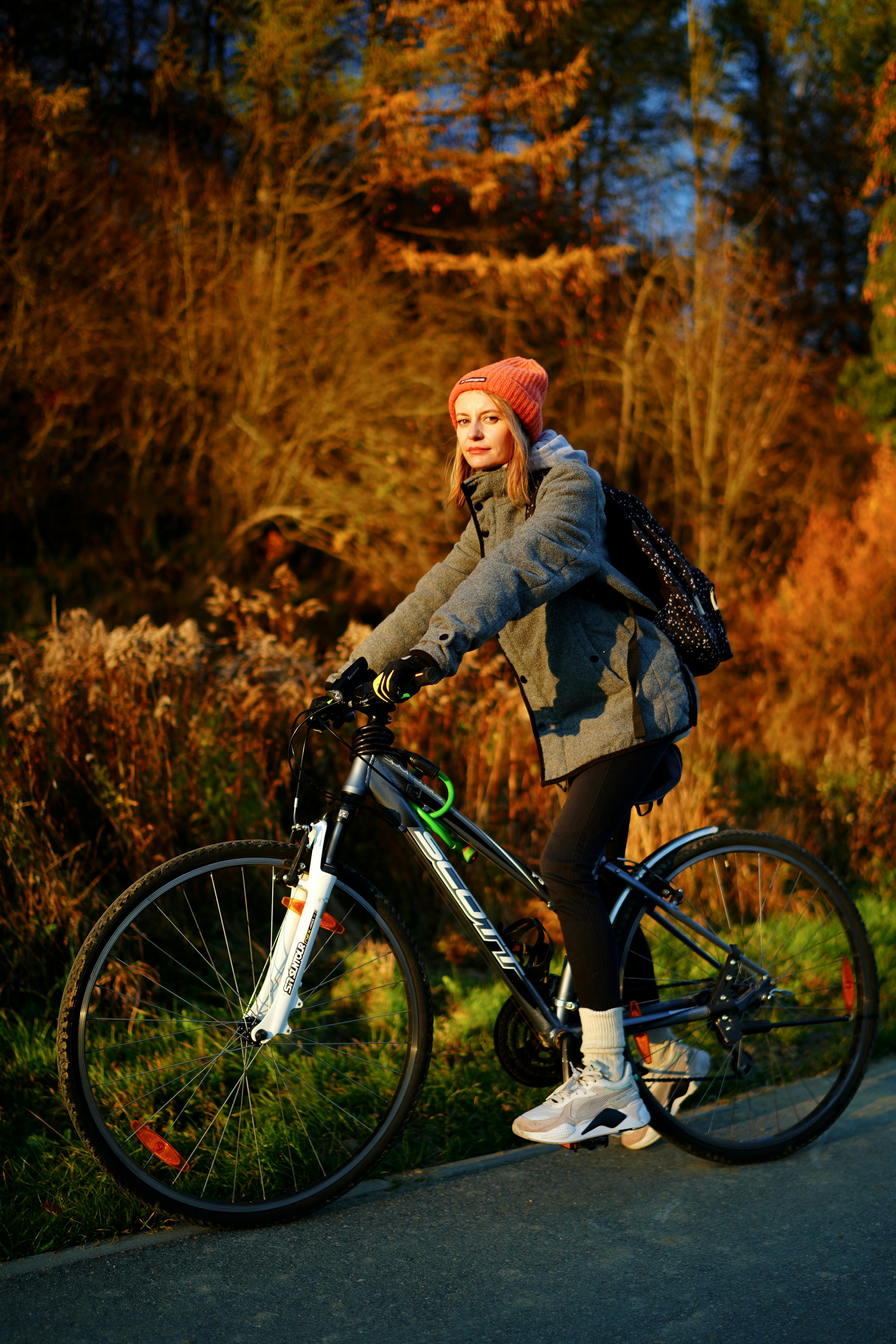 A woman rides a bicycle on a scenic autumn path, showcasing vibrant fall colors.