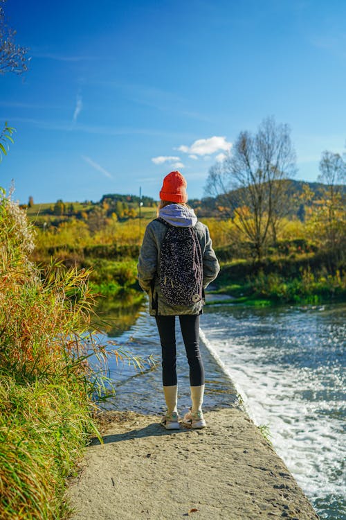 Free A woman with a backpack standing on a bridge looking at the water Stock Photo
