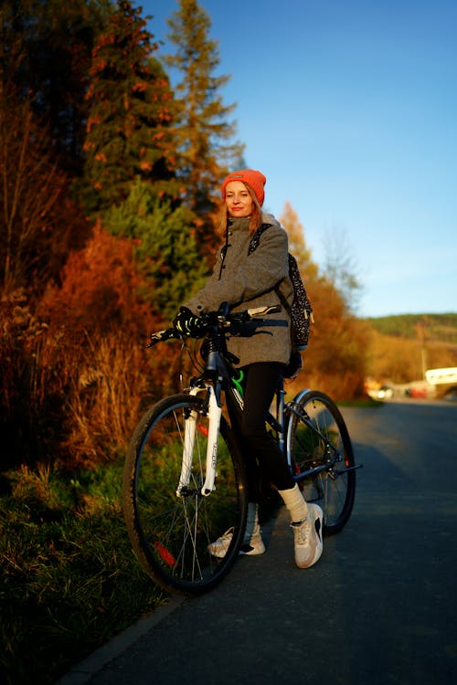 A woman is standing on a bike with a helmet