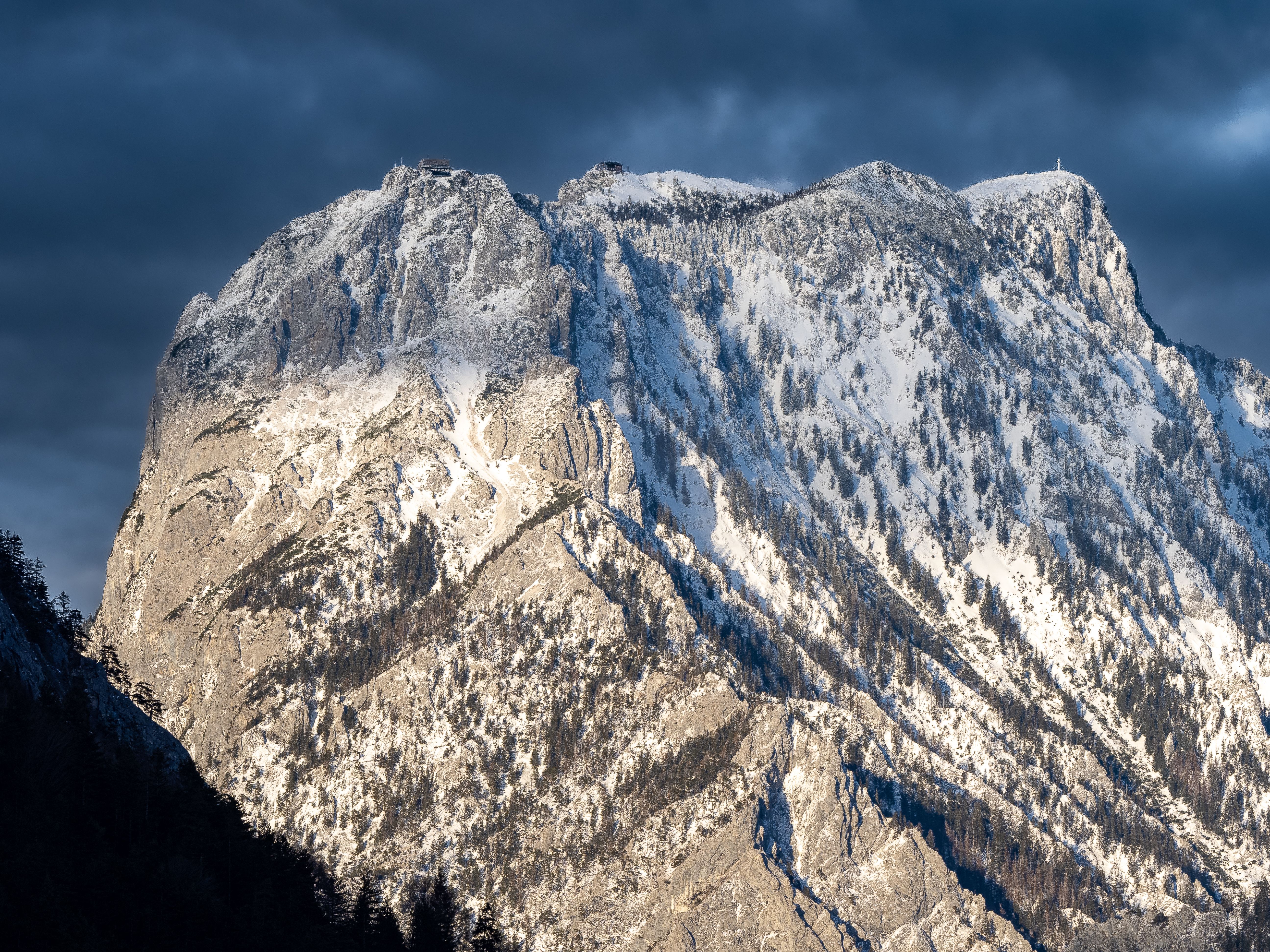 Majestic view of Traunstein mountain in Gmunden, Austria, covered in snow under a dramatic sky.