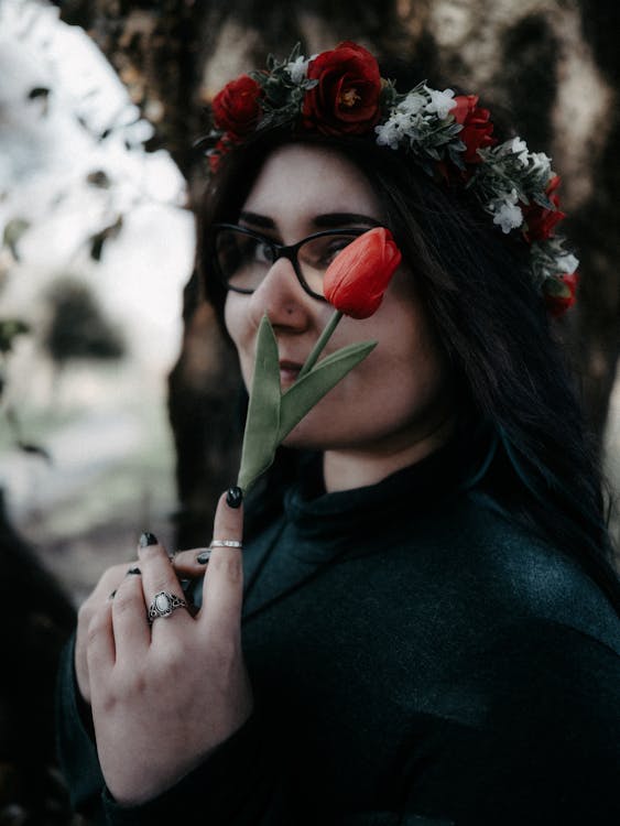 A woman with a flower crown on her head holding a red flower