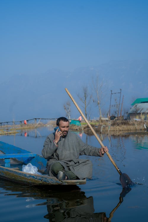 Man Using a Smartphone on a Rowboat