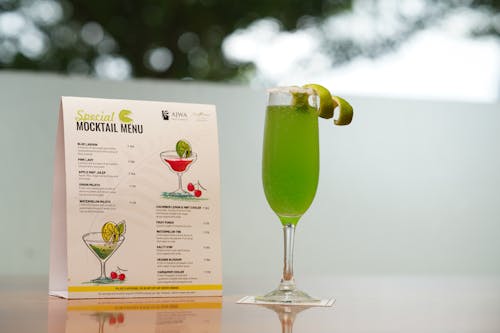 A cocktail with lime and a menu on a table