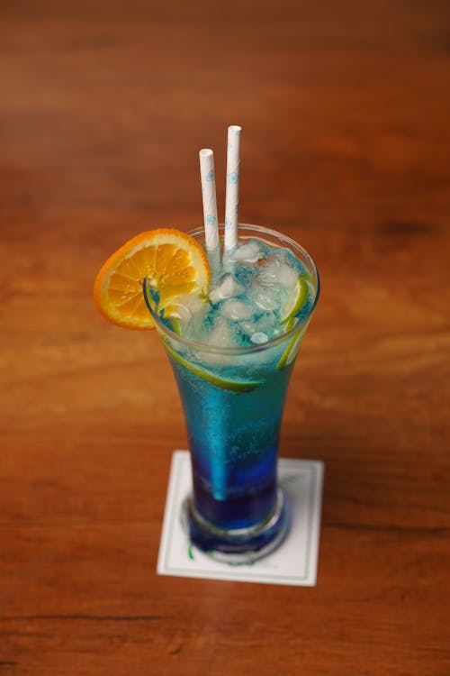 A blue drink with orange slices and a straw