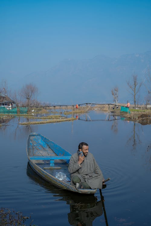 Man Using a Smartphone on a Rowboat