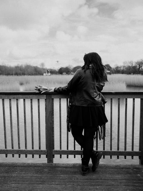 A woman standing on a wooden bridge looking out over a lake