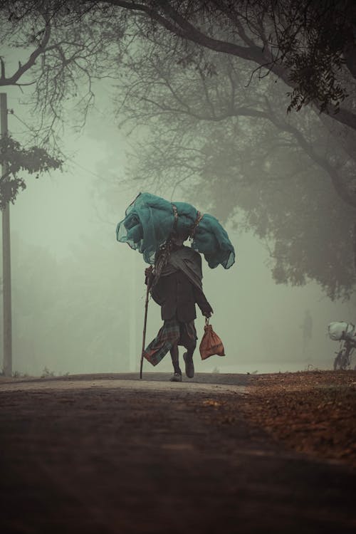 A person walking down a foggy road with an umbrella