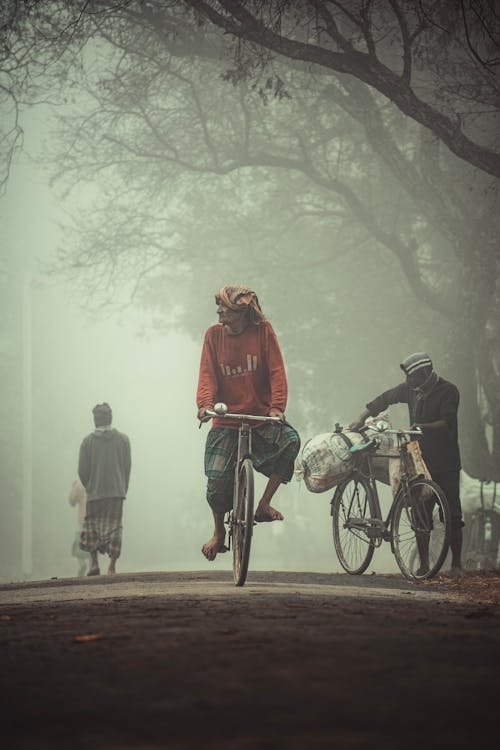 A man on a bicycle rides through a foggy street