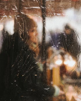 Blurred view of a woman in Berlin through a rainy window at a bustling market.
