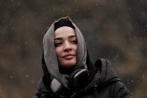 A woman wearing headphones and a hoodie in the snow