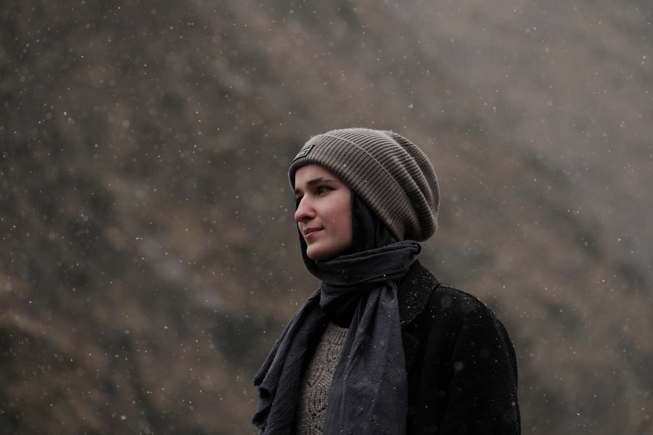 Woman in a gray beanie and dark scarf in falling snow