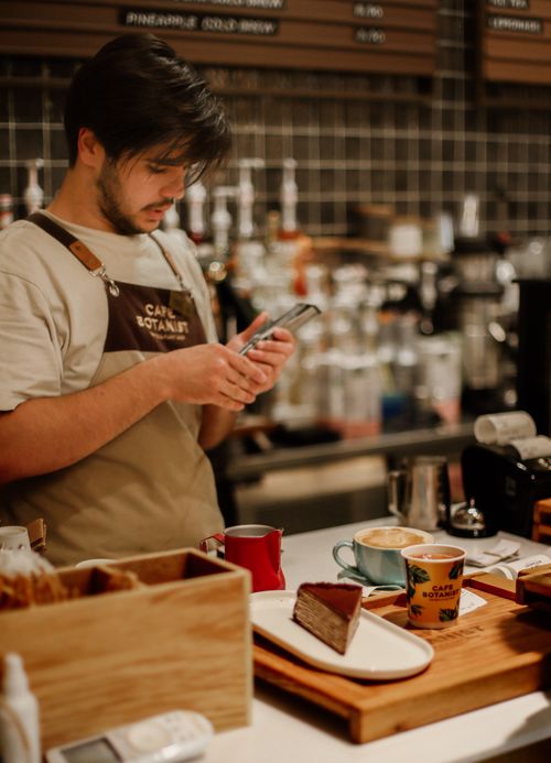 Free A barista working in a café in Baku, Azerbaijan, stands at the counter preparing drinks and desserts. Stock Photo