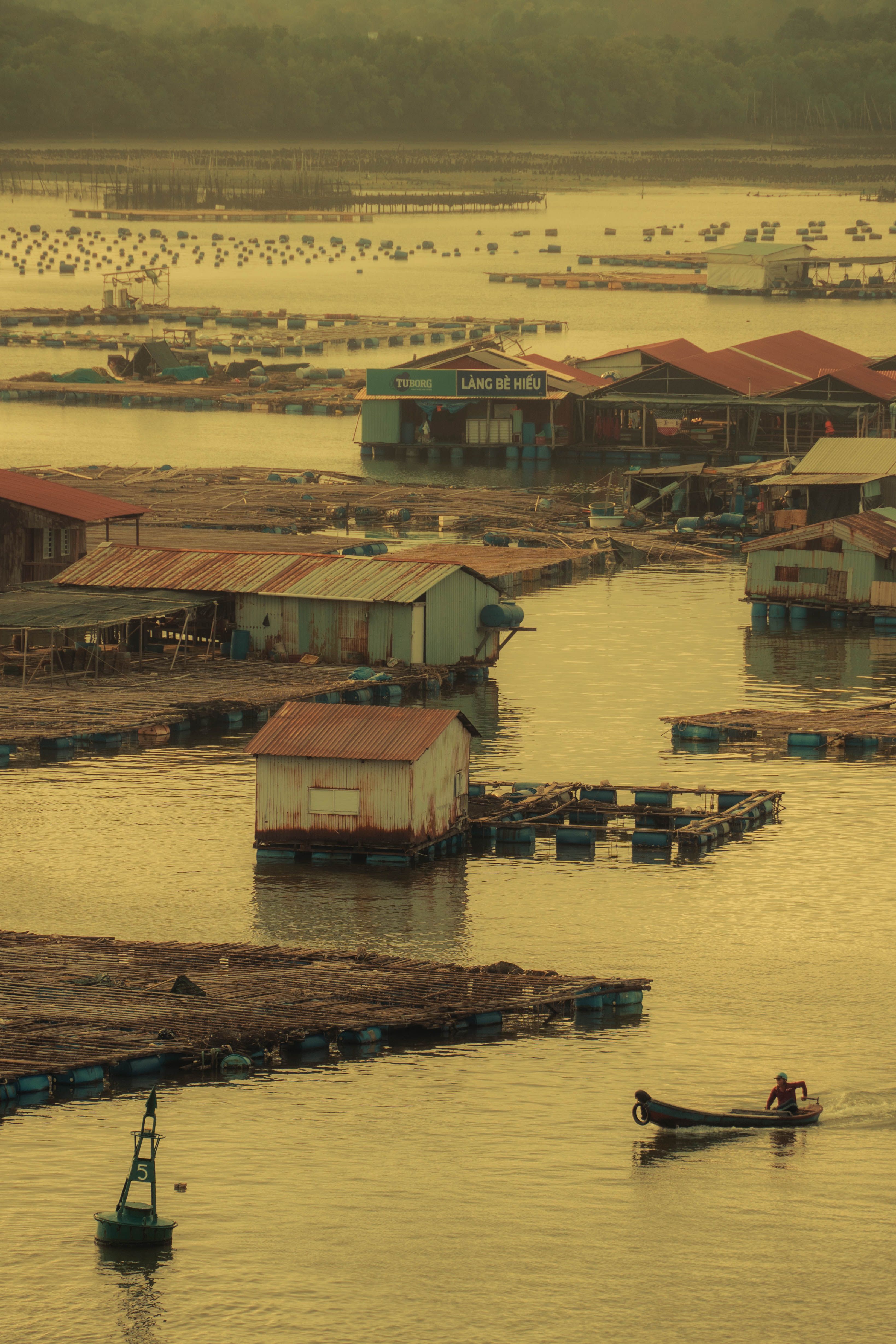Beautiful view of a fishing village by the river at sunset, with boats and huts.