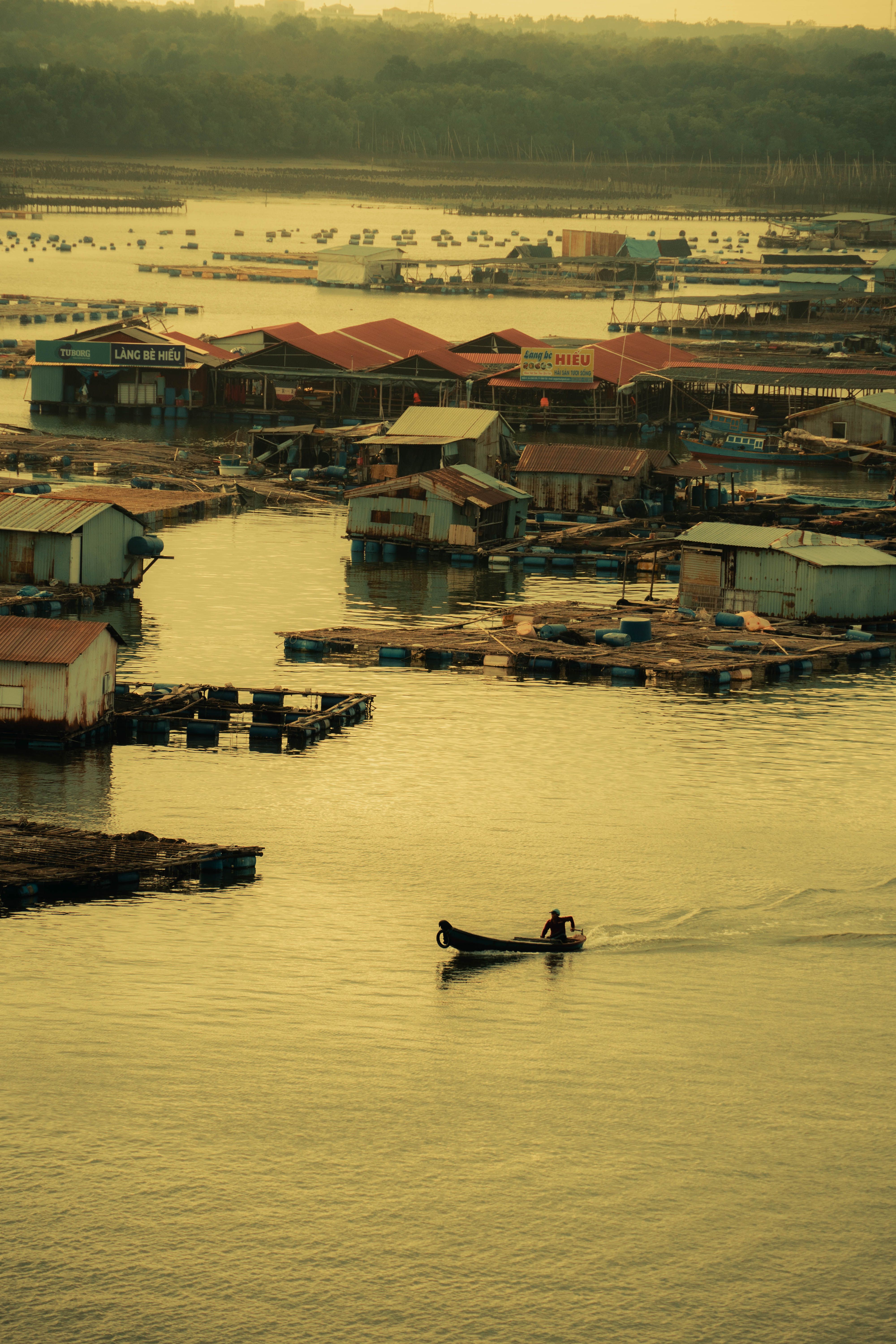 Serene village with stilt houses and boats on a tranquil waterway at sunset.