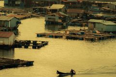 Serene village with stilt houses and boats on a tranquil waterway at sunset.