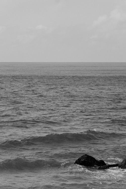 A black and white photo of a person standing on the beach