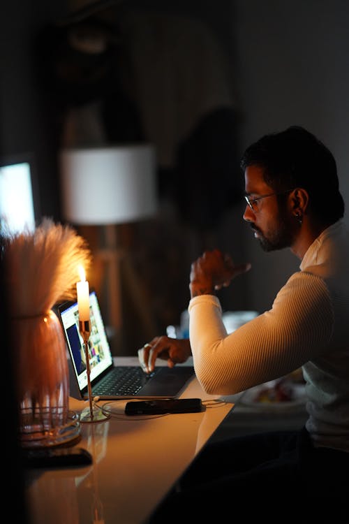Man Working on a Laptop by Candlelight