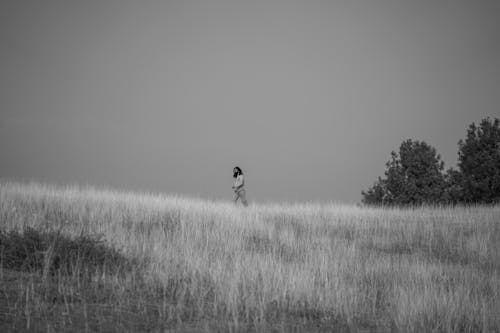 Free Black and White Photo of a Bearded Man Walking on a Grass Field  Stock Photo