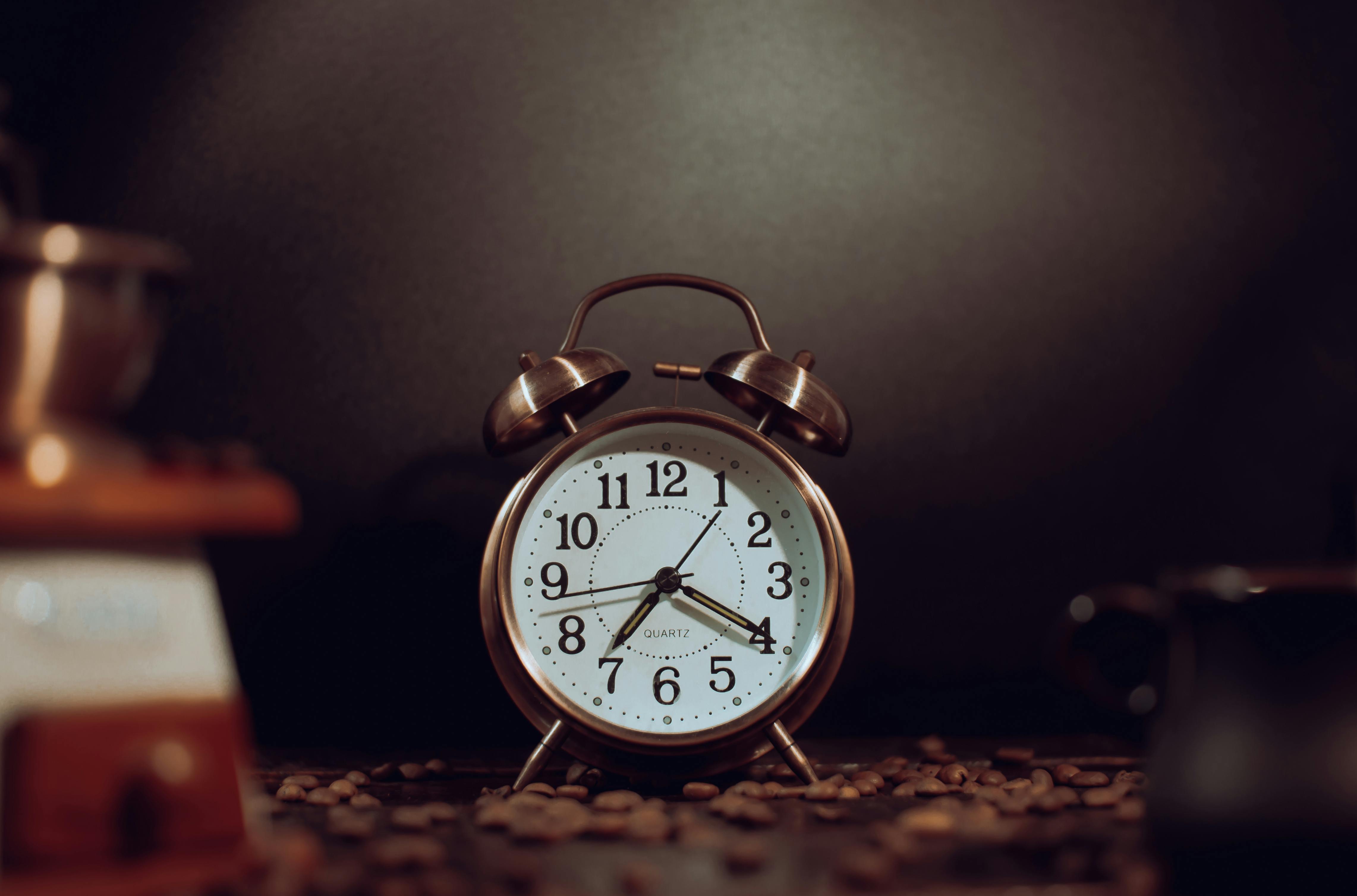 Rustic vintage alarm clock surrounded by coffee beans, providing a warm nostalgic feel.
