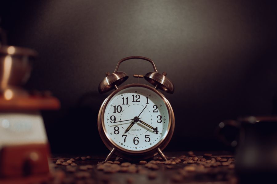 Rustic vintage alarm clock surrounded by coffee beans, providing a warm nostalgic feel.