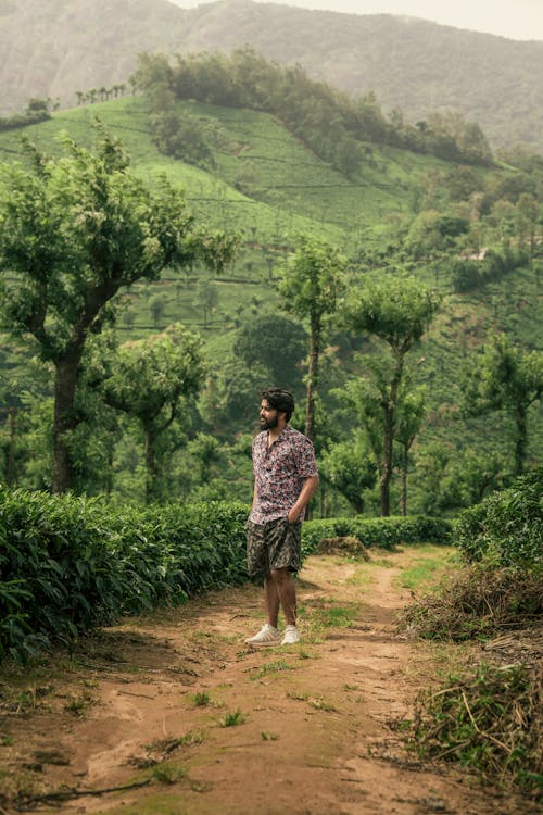 Man in Shirt and Shorts Standing on Footpath in Countryside