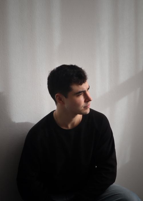 Free Portrait of a young man sitting indoors, deep in thought. Stock Photo