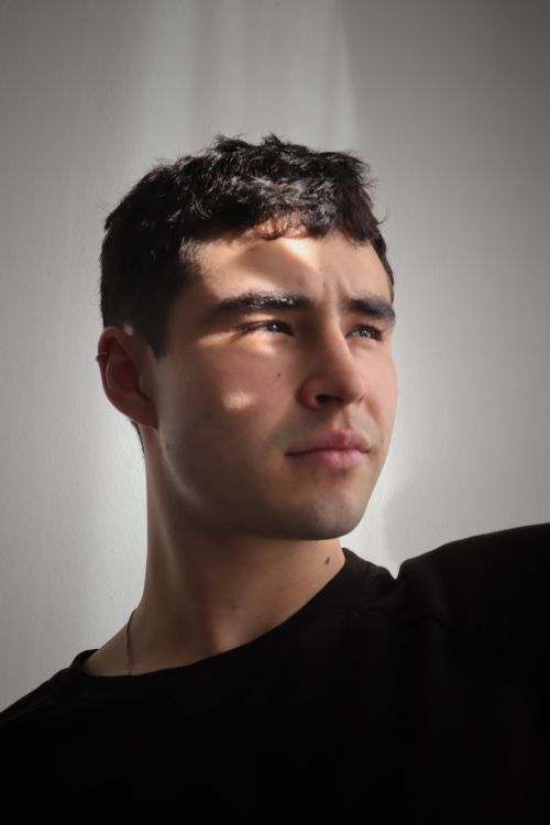 Free Portrait of a young man with natural lighting on a white background, evoking a thoughtful mood. Stock Photo